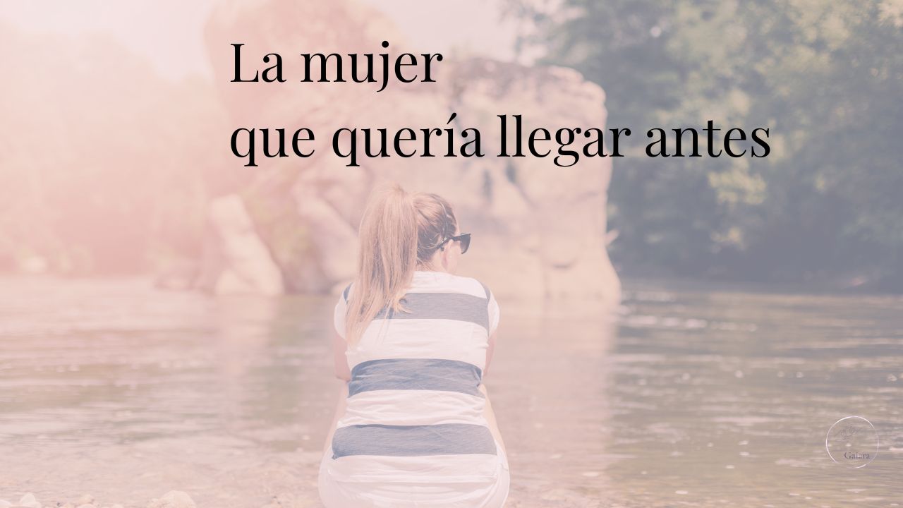 Mujer sentada de espaldas junto a un río, observando el agua en un momento de calma y presencia.